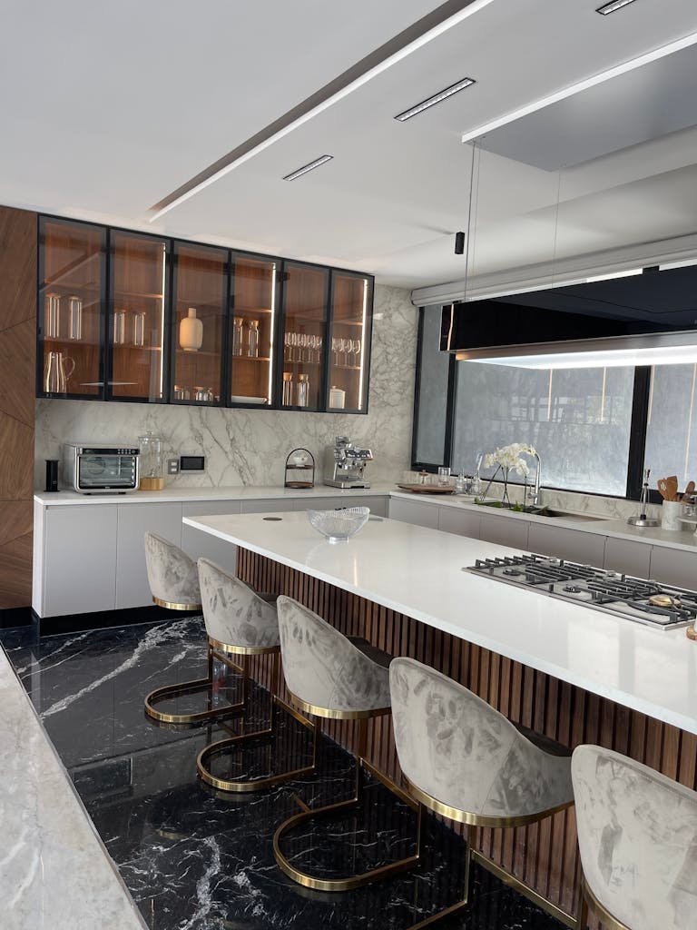 Photo by Jennifer Perez Flores Elegant kitchen featuring a marble island, modern seating, and sleek cabinetry.